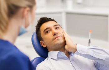 A dentist consulting a male patient with TMJ.