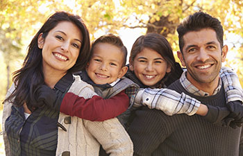 Portrait of happy parents piggybacking kids outdoors.