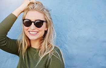 Happy, smilling blonde woman wearing sunglasses.