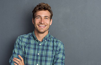 Young smiling handsome man standing with his arms folded. Marietta GA Orthodontics.