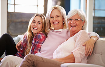 Grandmother with her daughter and granddaughter sitting on a sofa.