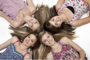 Four young girls laying on the ground.