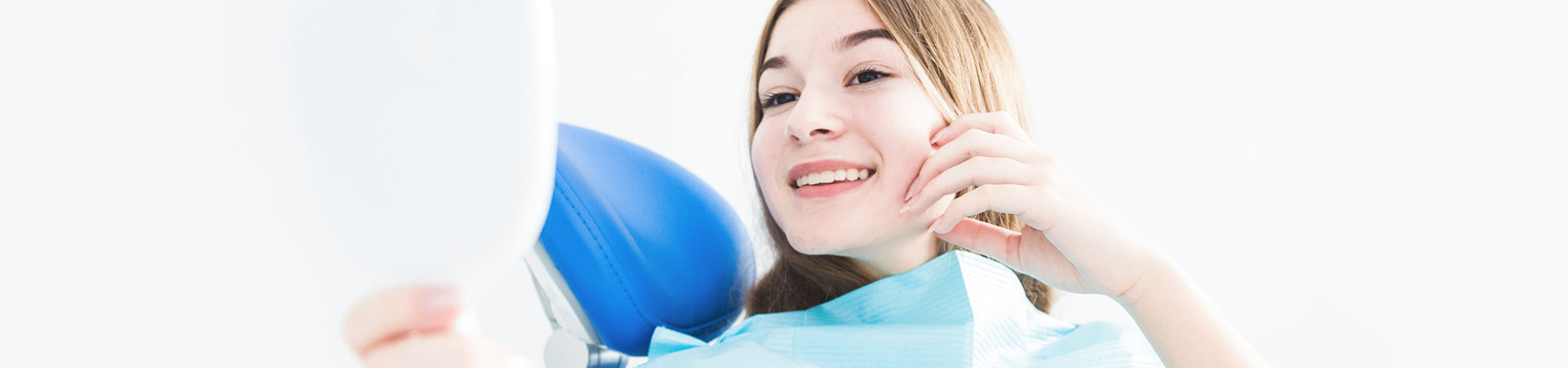 Woman checking teeth at dental mirror.