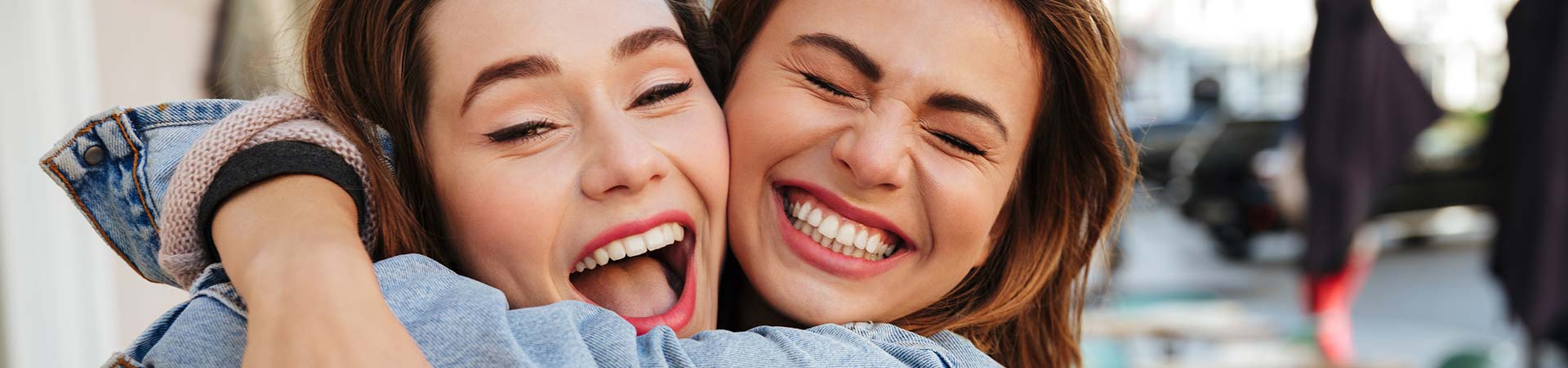 Two happy hugging each other women friends with perfect smiles.