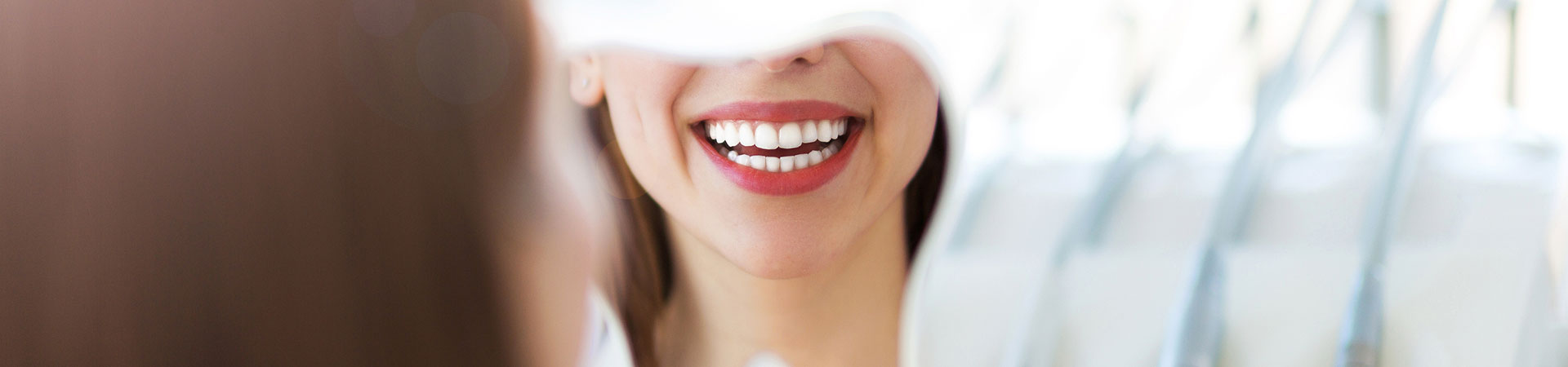 Woman looking at her beautiful teeth in a mirror. Oral hygiene Marietta, GA.