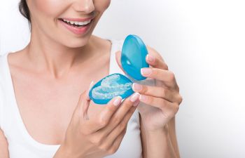 Woman opening a blue plastic case with clear retainers.