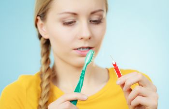 Young woman wearing dental braces with a traditional and a Proxy dental brush.
