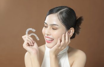 happy woman holds invisalign in hand 1